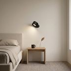 Small black wall lamp in a bedroom with a soft warm-white wall